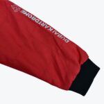 A close-up view of a red quilted jacket sleeve featuring the white embroidered text DUBAI KARTDROME and a black cuff.