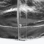 Close-up of a shiny, reflective silver metallic fabric with prominent stitched seams.