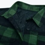 Close-up of a green and black plaid shirt jacket with a quilted lining, snap buttons, and a black shoulder yoke.