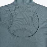 Close-up of the back of a slate blue activewear top featuring a unique geometric cutout design with curved piped borders.