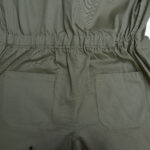 Close-up of the back of an olive green jumpsuit showing an elastic waistband and two patch pockets.