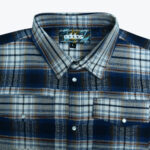 Close-up of a blue, white, and brown plaid flannel shirt with pearl snap buttons and chest pockets.