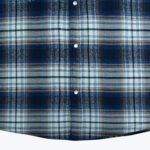 Close-up of a blue, white, and brown plaid flannel shirt with three white snap buttons down the center.