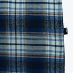 Close-up of a blue, white, and brown plaid patterned fabric with a small black tag on the right edge.