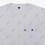 A close-up of a white crewneck shirt with a repeating grey addos text pattern and a buttoned chest pocket.