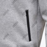 Close-up of a grey heather Addos jacket featuring a vertical black zipper pocket.
