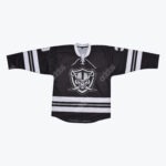 A black hockey jersey with a white lace-up collar, white stripes on the sleeves and hem, and a central logo of a skull wearing a raider helmet inside a shield.