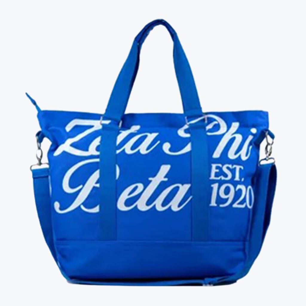 A royal blue tote bag featuring the white text Zeta Phi Beta and EST. 1920 with carrying handles and a shoulder strap.