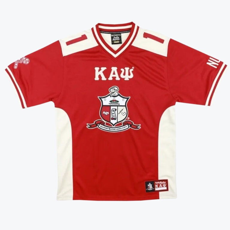 A red short-sleeved jersey featuring white side panels and shoulder accents. The front proudly displays the Greek letters Kappa, Alpha, Psi and the official Kappa Alpha Psi crest.