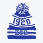 A blue and white knit pom-pom beanie with '1920' knitted on the crown and the Greek letters Zeta Phi Beta embroidered on the cuff.