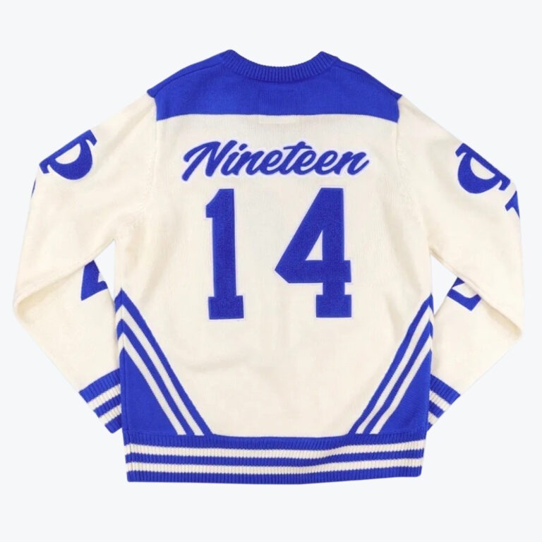 Back view of a cream and blue knit sweater with Nineteen 14 printed on the back in varsity style.