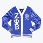 A royal blue cardigan with sequined sleeves, featuring the Zeta Phi Beta Greek letters and crest in white.