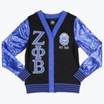 A black cardigan with royal blue sequined sleeves, featuring the Greek letters Zeta Phi Beta on the left and the sorority crest with EST. 1920 on the right.
